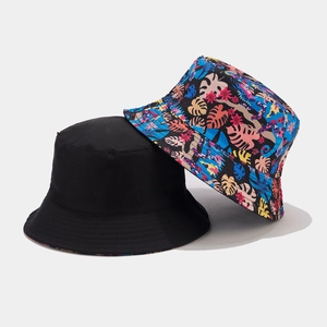 Dettagli di cappelli alla pescatora neri e con stampa a foglie tropicali per il sole