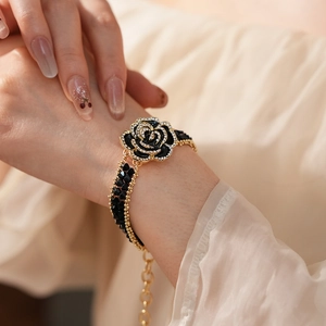 Detail of a black rose bracelet with crystal edges and gold chain on a female wrist