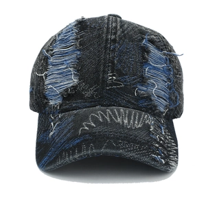 Close-up detail of distressed denim baseball cap with vintage frayed edges and holes