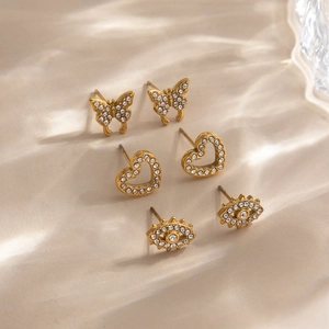 Three-pair gold earring set featuring rhinestone butterfly, hollow heart, and evil eye designs