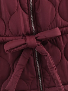 Close-up of wine red quilted jacket featuring metal zipper and drawstring waist tie detail
