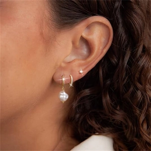 Close-up of gold s925 silver earring set with pearl drop and zircon studs on ear