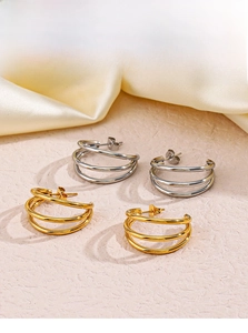 Detailed view of triple-layered hoop earrings in 18K gold and silver finishes