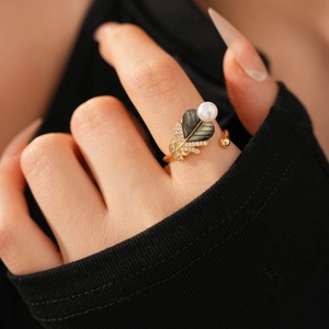 Detail of vintage gold ring featuring a black shell leaf with pearl and zircon accents
