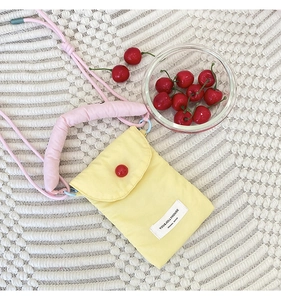 Top view of a yellow canvas phone bag with pink rope straps and red button detail