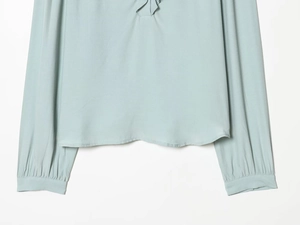 Detail of light blue viscose top showing ruffles, sleeve cuffs and fabric texture