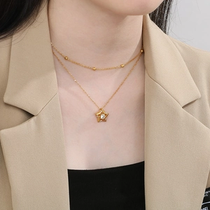 Detail of 18K gold-plated double-layer necklace with star pendant worn on model neck