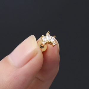 Dettaglio macro di piercing per cartilagine a corona dorata con zirconi micro-incastonati