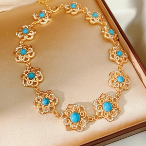 Close-up of vintage gold floral necklace with blue turquoise and crystals in a gift box