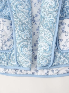 Detailed macro view of blue paisley quilted fabric texture with contrast piping