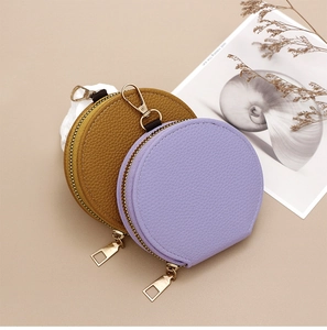 Detailed view of round litchi grain coin purses in brown and lilac with metal zippers