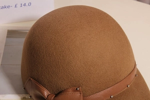 Detail of brown wool riding hat showing texture leather strap and bow with rhinestones