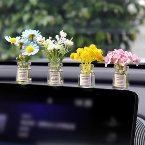 Four mini glass vases with glowing artificial flowers on car dashboard with Good Luck labels
