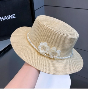 Detail of straw boater hat featuring elegant pearl chain and white floral accents