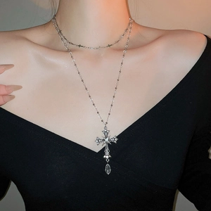 Detail of elegant double-layer silver cross necklace with crystal teardrop pendant