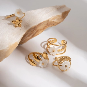 Detail of four golden 18K flower rings with crystals on natural stone display