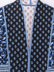 Close-up detail of paisley trim and floral lining on a quilted reversible jacket