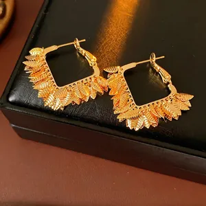 Gold-plated square hoop earrings with textured leaf tassels on black leather base