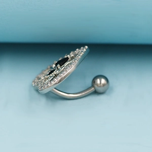 Detailed side view of the curved steel belly ring bar with black and white zircon
