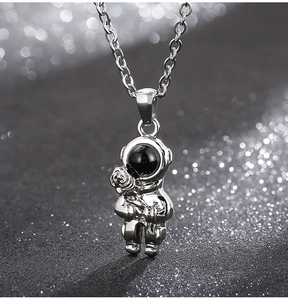 Detailed close-up of astronaut pendant necklace with black gemstone helmet and silver chain