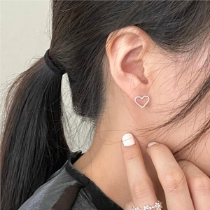 Close-up of minimalist silver heart stud earrings with beaded edge worn by a model