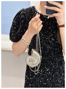 Close-up of a mini silver nautilus shell bag with bead chain on a sequin dress