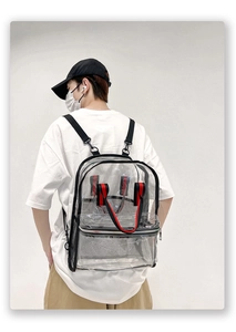 Detailed view of clear PVC backpack with red accents and mesh side pockets on a model