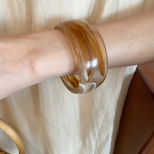 Close-up of wide amber acrylic resin bangle with vintage marble texture on wrist