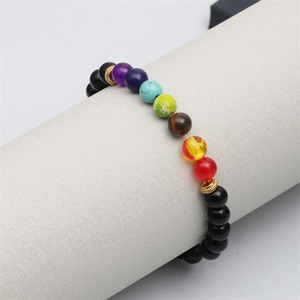 Détail du bracelet en perles des sept chakras sur support gris avec séparateurs dorés
