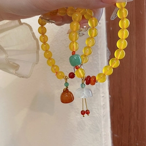 Nahaufnahme von gelben Perlenarmbändern mit Blumen- und Flaschenkürbis-Anhängern