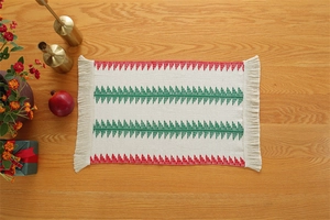 Close-up of woven cotton Christmas table runner with red and green geometric tassel detail
