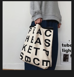 Close-up of minimalist beige canvas tote bag with bold black letter typography design