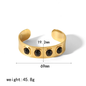 Gold geometric stainless steel bangle with four black round gemstones on a white base