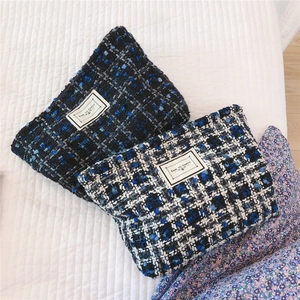 Detailed close-up of blue and white tweed cosmetic bags with woven texture and labels