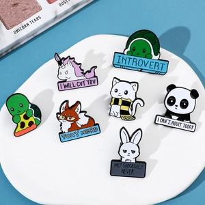 Close-up of seven cartoon animal enamel pins with slogans displayed on a white plate