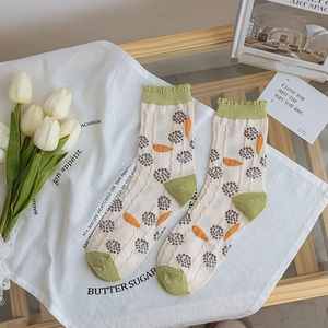 Close-up of knit crew socks with carrot embroidery and green frill trim details