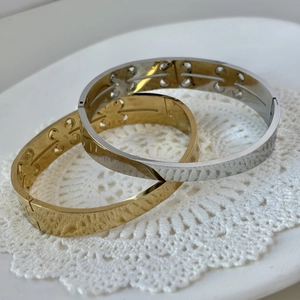 Crossed gold and silver stainless steel magnetic bracelets on white lace background
