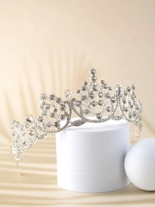 Detailed view of silver crystal bridal crown with floral rhinestone motifs on stand