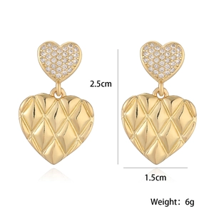 Detailed view of 18K gold heart earrings with zircon inlay and quilted texture pattern