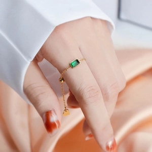 Gold-plated chain ring with emerald zircon and heart charm on soft satin fabric
