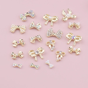 Collection de nœuds en alliage doré pour ongles avec perles et strass sur fond rose