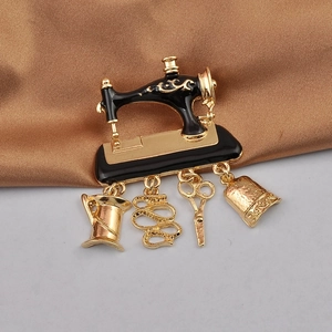 Detail of a vintage black sewing machine brooch with gold charms like scissors and iron