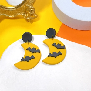 Detail of Halloween drop earrings featuring a yellow moon and black bat made of polymer clay