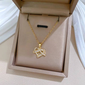 Close-up of golden heart pendant necklace with zircon pavé in a brown jewelry gift box