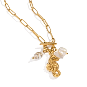 Detail view of 18K gold seahorse pendant with pearl and shell on paperclip chain