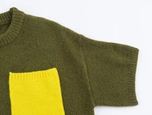 Detailed macro view of dark green knit sweater featuring a contrasting yellow front pocket