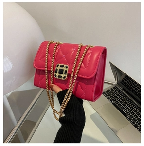 Detail of rose red quilted faux leather handbag featuring a gold chain and jewel clasp
