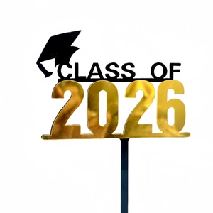 Macro detail of Class of 2026 graduation cake topper with gold acrylic numbers and black cap