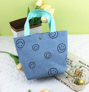 Détail du sac en velours côtelé bleu avec motifs smiley noirs et bouton pression