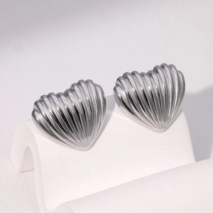 Macro detail of silver heart-shaped stud earrings with trendy textured striped surface
